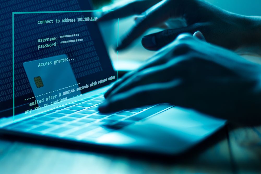 A hacker using a laptop to steal payment details and commit fraud